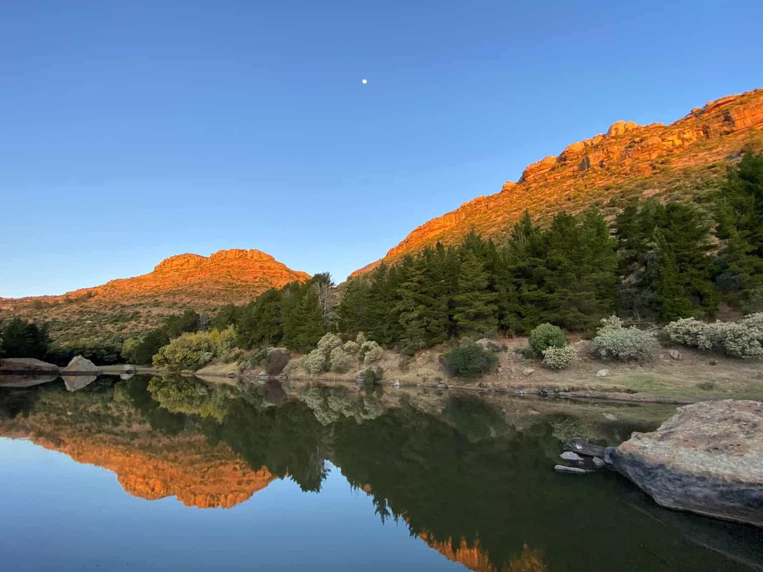Majestic mountains of Lesotho reflected in calm waters at golden hour
